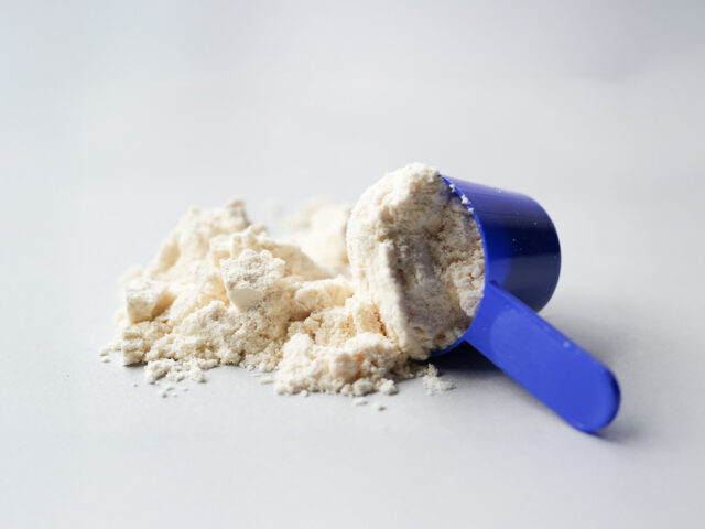 Scoop of white powder supplement with text "Does Creatine Cause Hair Loss? "The Truth Behind the Myth.